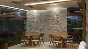 A modern interior with a stone wall, wooden furniture, and large windows. - Makia Beach Resort Experience By All (Ipojuca)