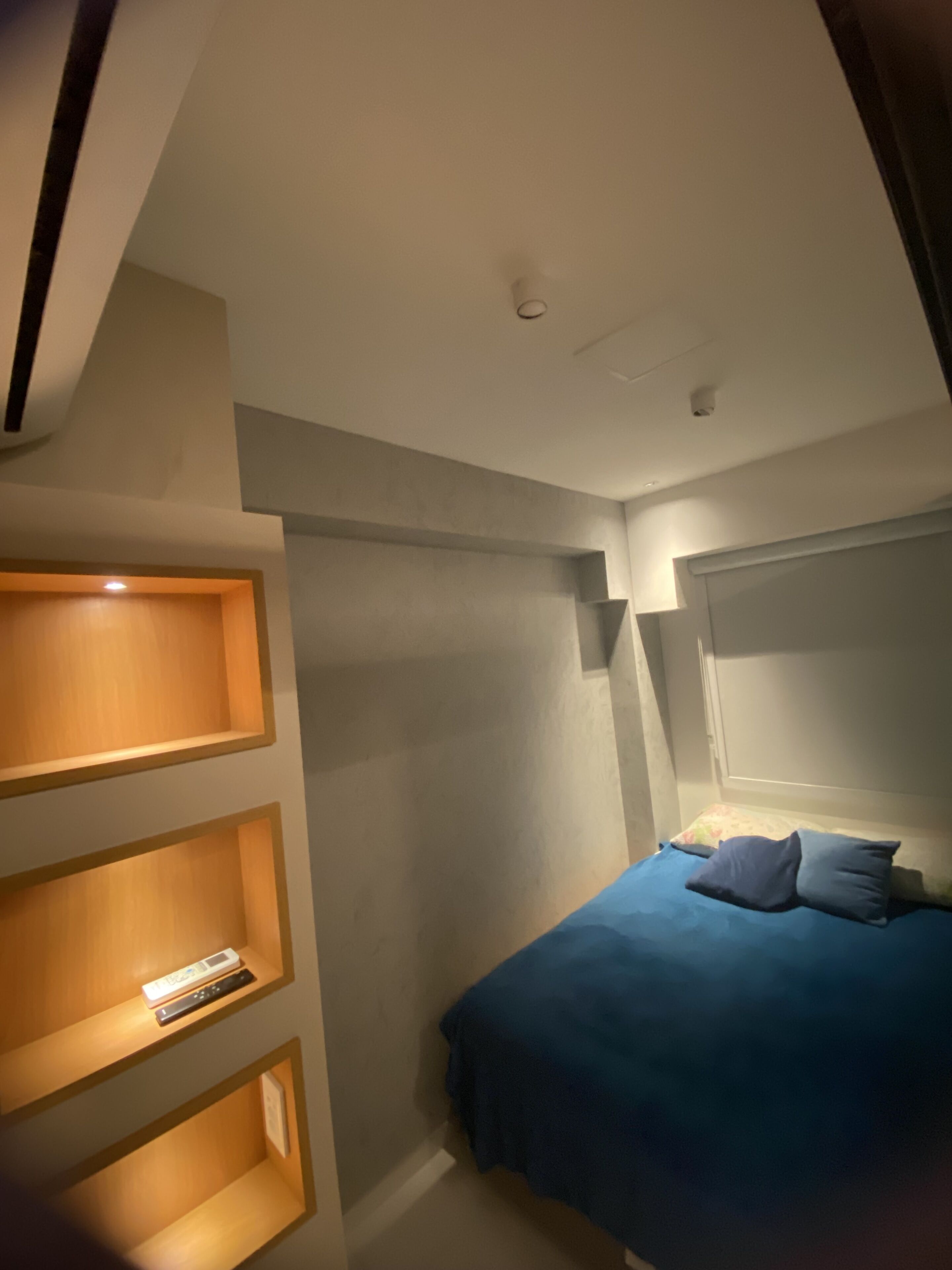 A bedroom with a bed, a nightstand, and built-in shelves.