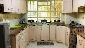 A kitchen with white cabinets, a tiled floor, a window with greenery outside, and a built-in stove.