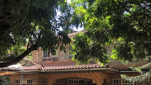 A small stone building with a tiled roof, a gated entrance, and a paved area in front.