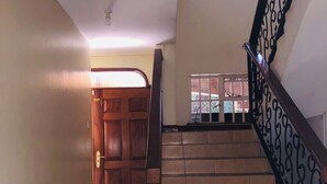 A staircase with a wooden handrail and black balusters, leading to a landing with a window.