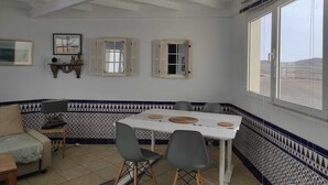 Een eetgedeelte met een tafel, stoelen en uitzicht door grote ramen.