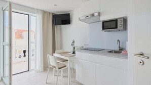 A modern kitchen with a built-in microwave, a small sink, and a dining area with a chair and table.