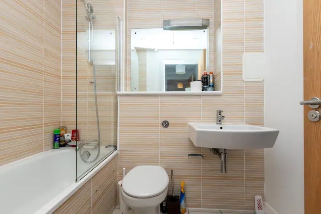 A bathroom with a bathtub, toilet, sink, and a glass shower enclosure.