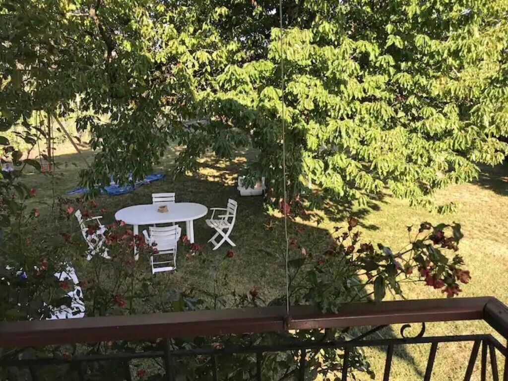 A garden with a round table and chairs, surrounded by lush greenery and flowering plants.