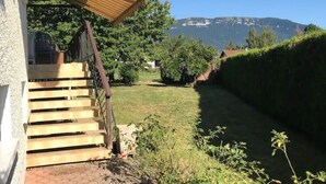 Een trap die leidt naar een overdekte veranda met uitzicht op een grasveld en bergen op de achtergrond.