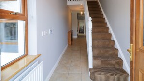 Un escalier avec une rampe blanche et une moquette à motifs, menant à un deuxième étage.