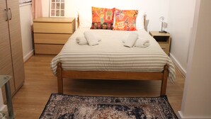 A neatly arranged bedroom with a bed, bedside tables, a dresser, and a rug. - Impeccable Spacious 6-bed House in Romford (Romford)