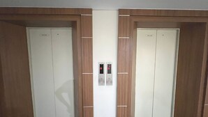 Deux portes d’ascenseur, avec un panneau de commande placé entre elles.