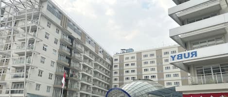 A multi-story hotel with a modern architectural design, featuring balconies and a glass facade.