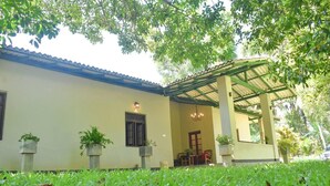 Uma casa com varanda coberta, plantas em vasos e gramado.
