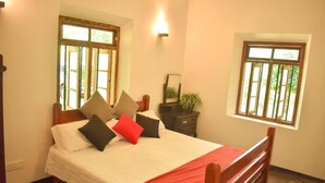 Quarto com cama, mesa de cabeceira, espelho e duas janelas.