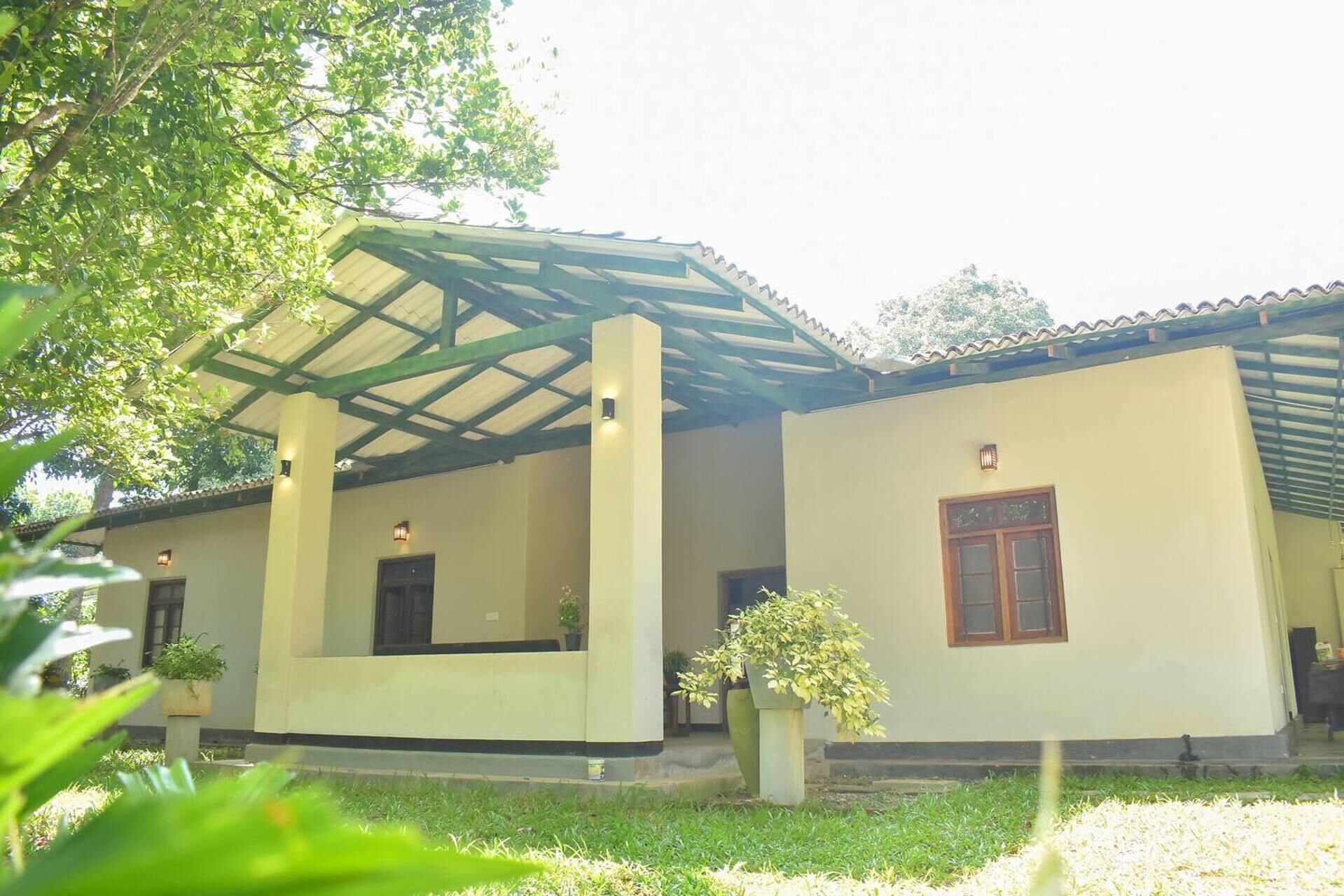 A building with a covered patio area, a small garden, and a single window with a door.