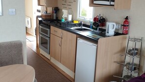 Une cuisine compacte avec des meubles en bois, un four à micro-ondes, un évier et une machine à café.