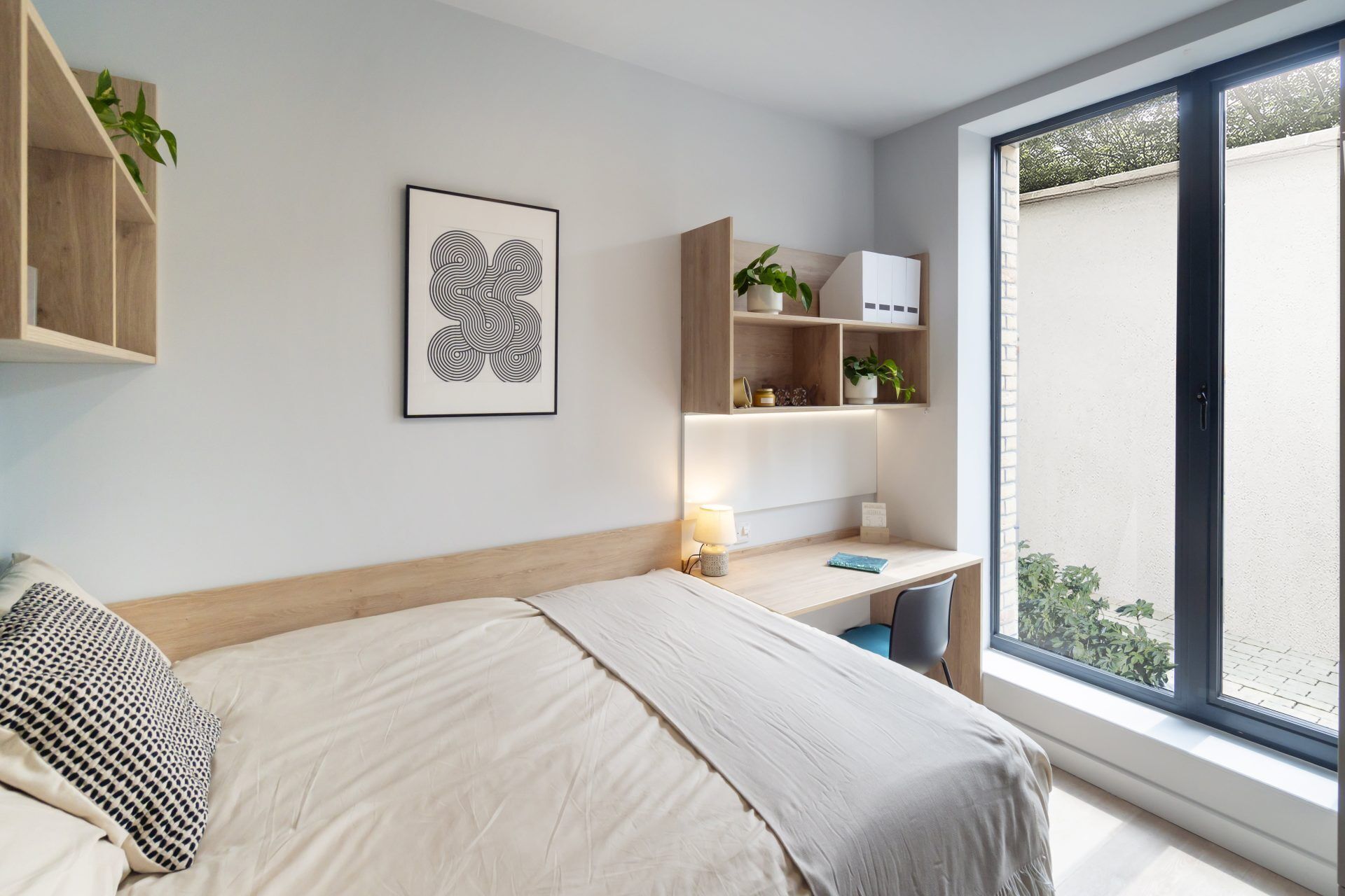 Ein modernes Schlafzimmer mit Bett, Schreibtisch und großem Fenster.