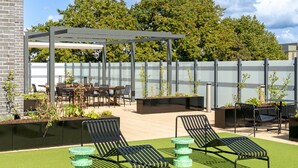 Un patio al aire libre con pérgola, sillones de descanso, una mesa de comedor y sillas.