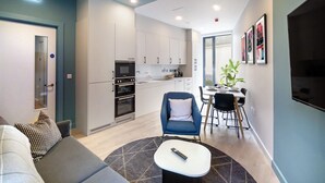 Un apartamento moderno con sala de estar, kitchenette, comedor y un amplio ventanal.