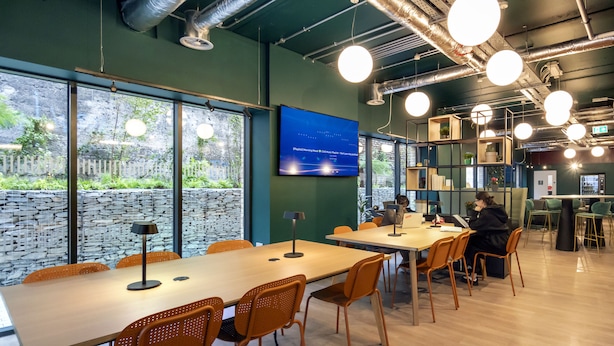 Una sala de conferencias moderna con ventanas amplias, un televisor de pantalla plana y una mesa de madera con sillas.