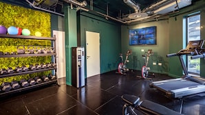 Un gimnasio con pesas rusas, mancuernas, cintas de correr y bicicletas estáticas.