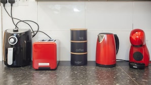 A kitchen counter with a toaster, a red coffee maker, a black and red kettle, and a black and red electric kettle. - Lovely 2 Bedroom House Sheffield Central Location (Sheffield)