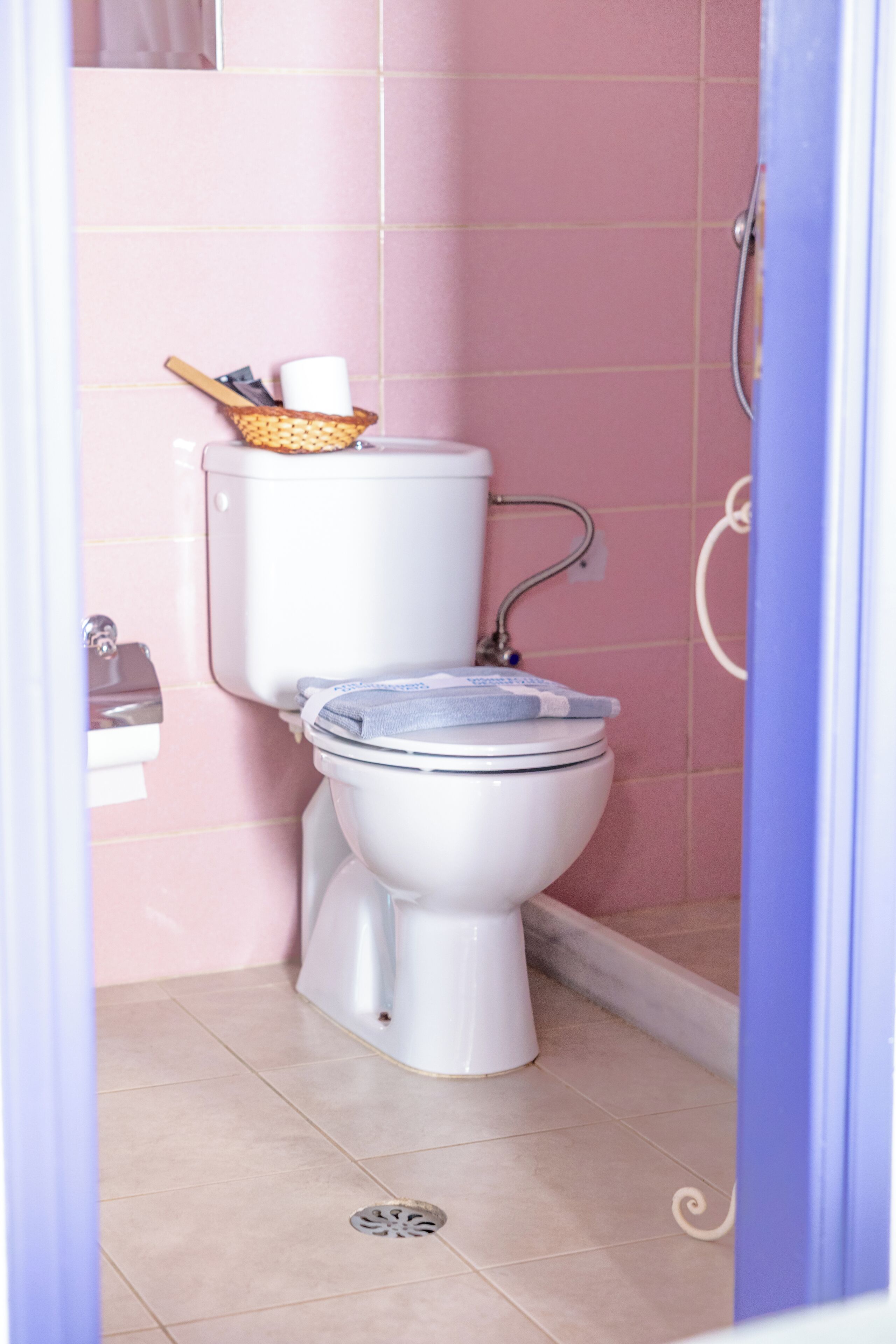 A bathroom with a toilet, a basket with a roll of toilet paper, and a shower area.