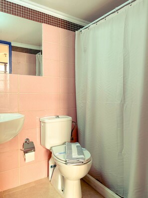 A bathroom with pink tiles, a white toilet, a white sink, and a shower curtain. - Kali Strata 2 - Downtown (Symi)
