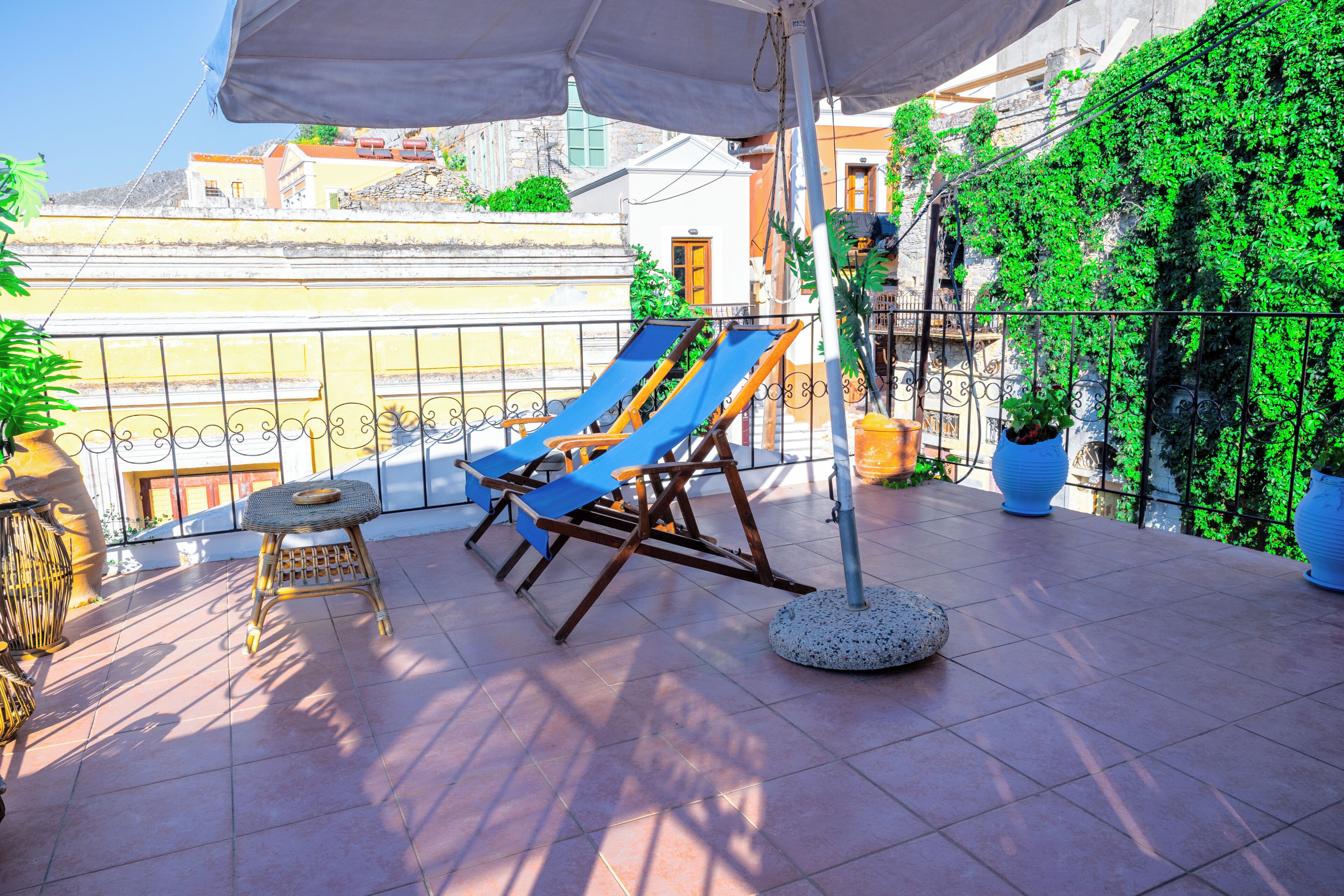 A terrace with a sun lounger, a small table, and potted plants.
