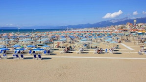 A beach with numerous umbrellas and sun loungers, a clear sky, and mountains in the background. - Comfortable Campsite-chalet G14 Tuscany Near sea (Viareggio)
