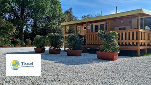 A wooden cabin with a covered porch, surrounded by gravel and potted plants. - Comfortable Campsite-chalet G14 Tuscany Near sea (Viareggio)