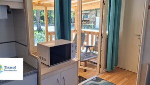 Una kitchenette con microondas, armarios y vista a la terraza exterior.
