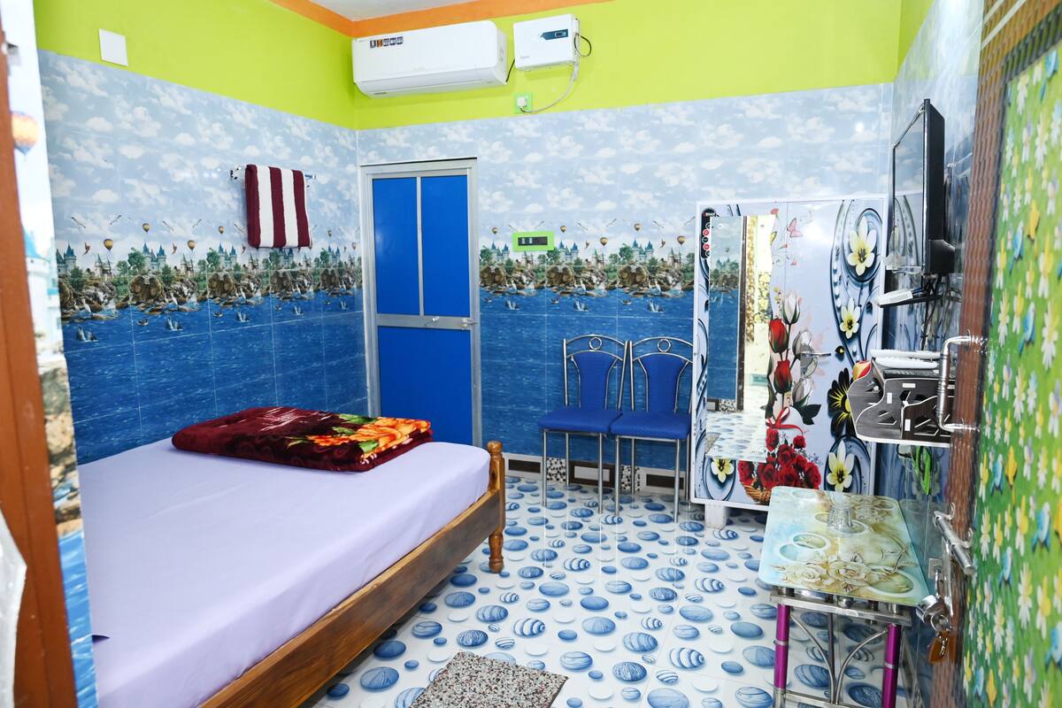 A room with a bed, a chair, a small table, and a TV.