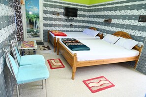 Una habitació d'hotel amb un llit gran, dues cadires, una taula petita i un televisor fixat a la paret.