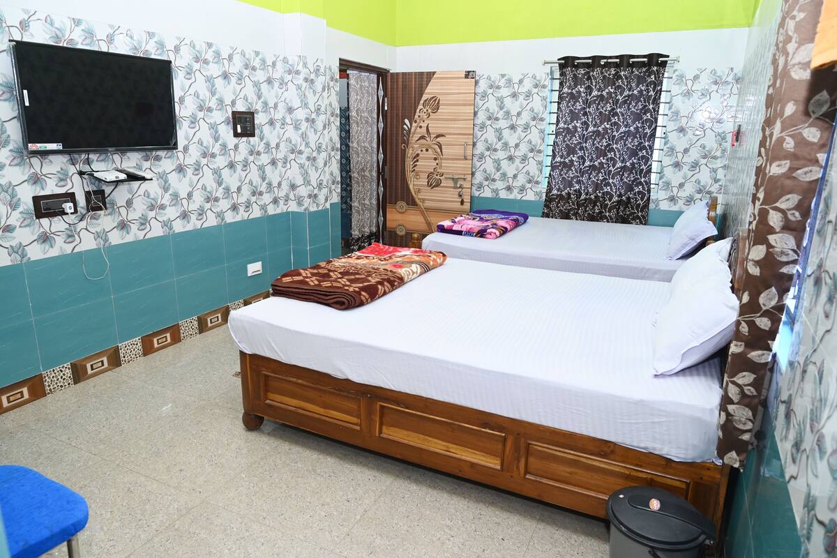 A bedroom with two beds, a TV, and a small table.