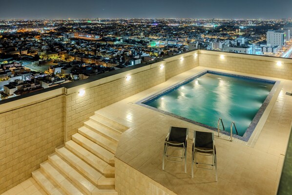 A rooftop pool with a city view, steps leading to the pool, and two lounge chairs. - Olaya 2 Stella Stays (Riyadh)
