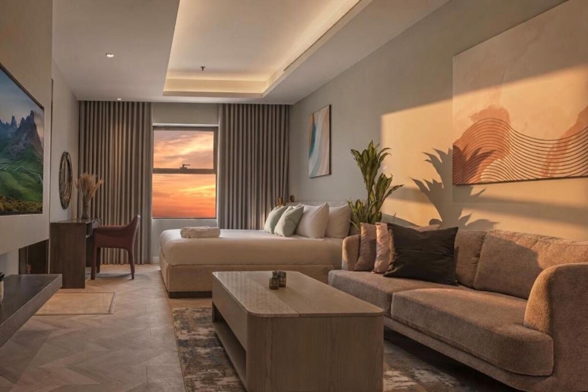 A modern living room with a sofa, coffee table, and a large window with curtains.