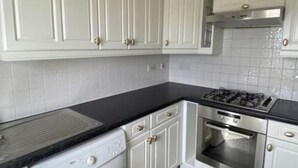 Una cucina con mobili bianchi, un piano di lavoro nero, un fornello a gas e un forno.