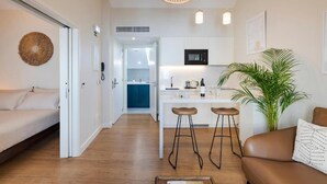 A modern apartment with a kitchenette, a dining area with stools, a sofa, and a large plant. - Montain View Guesthouse Pretoria (Pretoria)