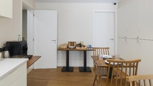 A compact kitchen with a coffee machine, a small table with a few items, and a dining area with chairs. - Montain View Guesthouse Pretoria (Pretoria)