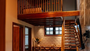 A loft-style room with a wooden staircase, a dining area with a table and chairs, and a sofa. - Espaco Villa Verde  (Ibiuna)