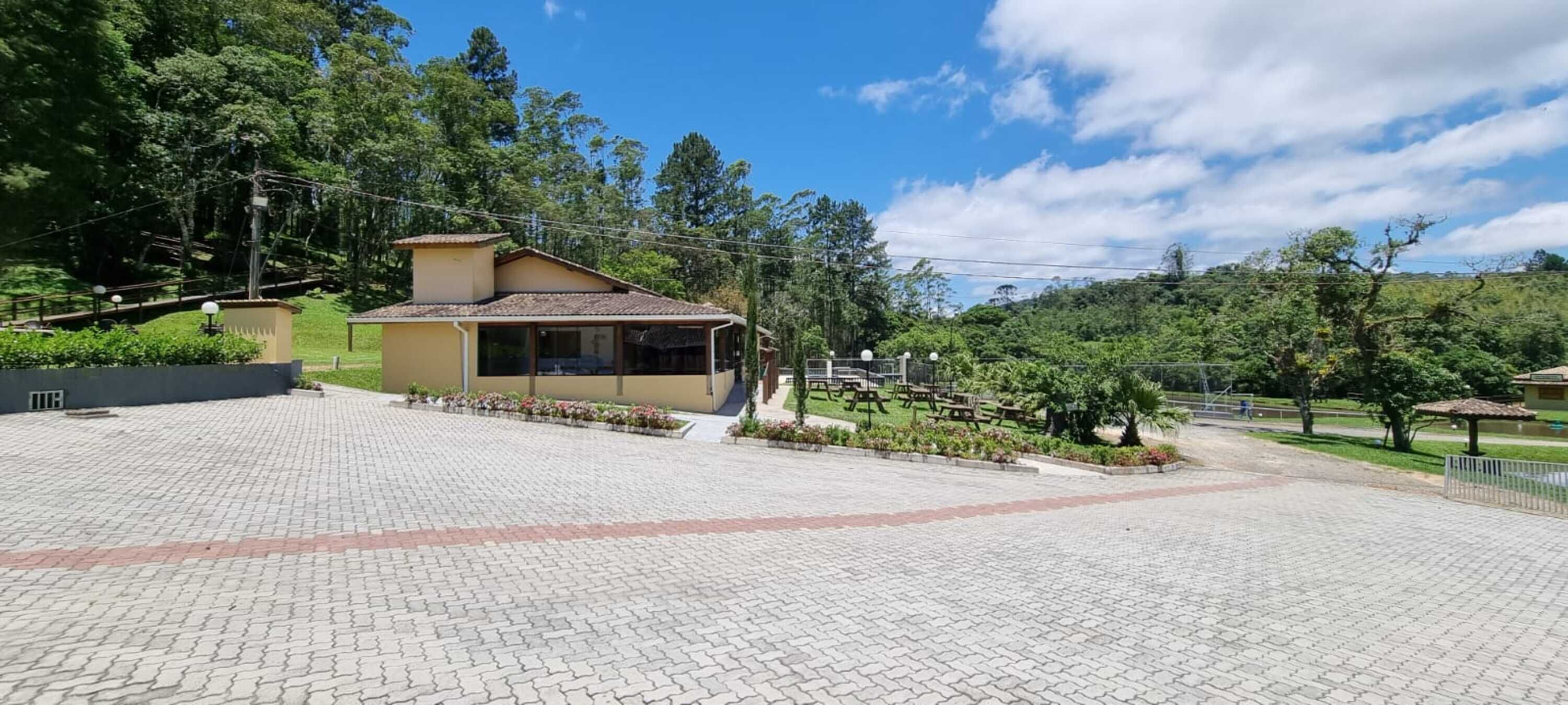 A paved courtyard with a small building, surrounded by greenery and trees.