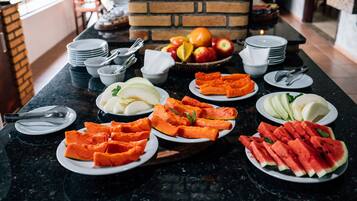 A breakfast buffet with various fruits and vegetables on a marble countertop.