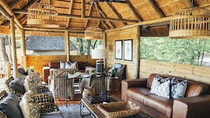 A cozy, rustic interior with wicker furniture, leather sofas, and a thatched roof. - Mankwe Tented Retreat (Maun)