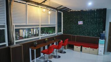 Una zona de bar moderna con taburetes rojos, una barra de madera y una pared cubierta de follaje verde.
