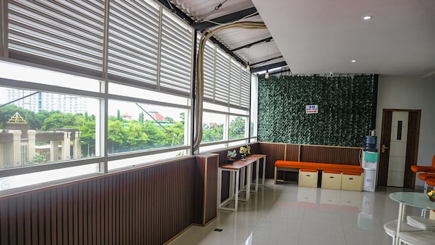 A modern interior with large windows, a green wall, a wooden bench, and a small table. - K1 UPN (Surabaya)