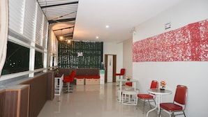 A modern hotel lobby with a seating area, a reception desk, and a decorative wall. - K1 UPN (Surabaya)