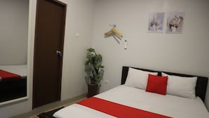 A neatly made bed with a red and white bedspread, a wooden headboard, and a small potted plant beside the bed. - K1 UPN (Surabaya)