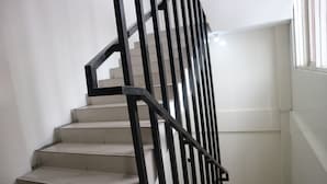 A staircase with a black metal railing and beige steps. - K1 UPN (Surabaya)