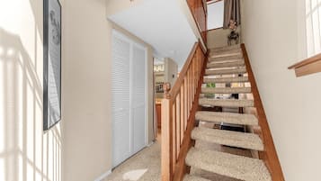A staircase with a wooden handrail and carpeted steps leading to a landing.