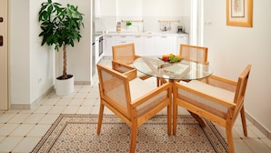 A modern kitchen with white cabinets, a dining table with four wooden chairs, and a potted plant. - Sun Spalato Harmony (Split)