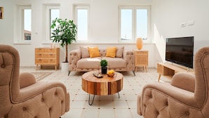 A living room with a beige sofa, two armchairs, a coffee table, and a TV. - Sun Spalato Harmony (Split)